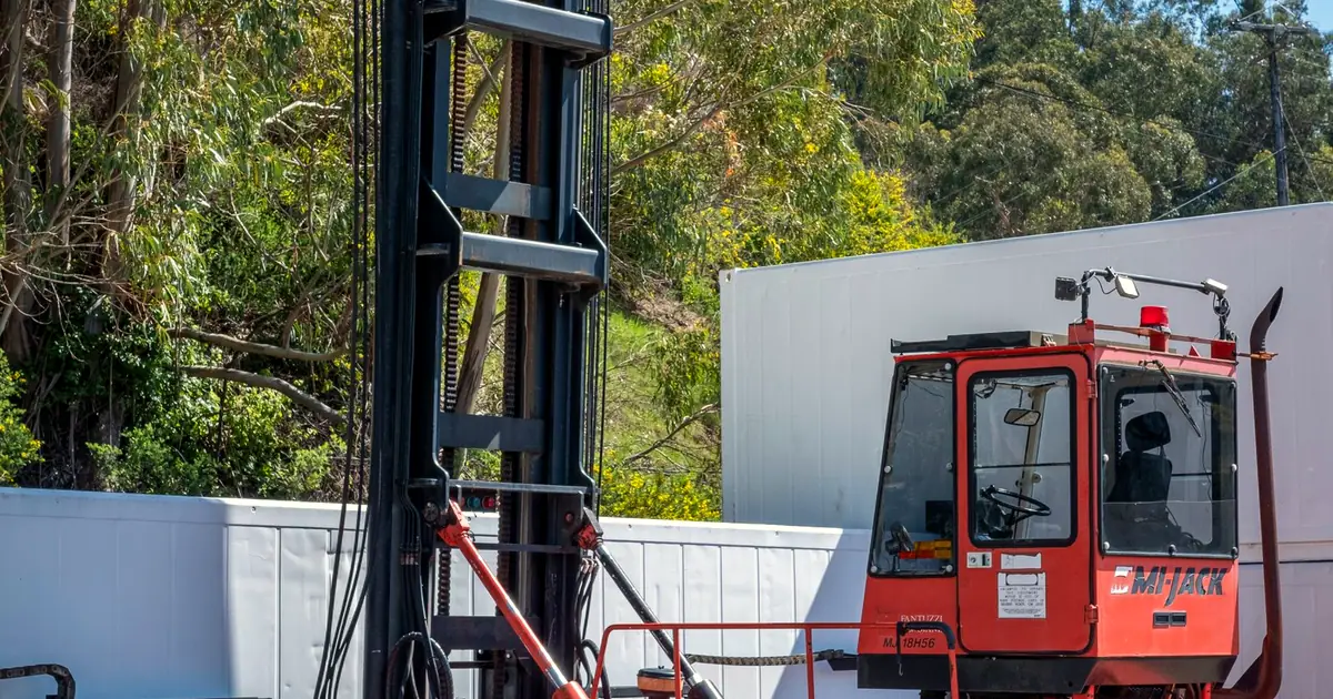 Heavy-duty forklift with a tall mast at an industrial yard