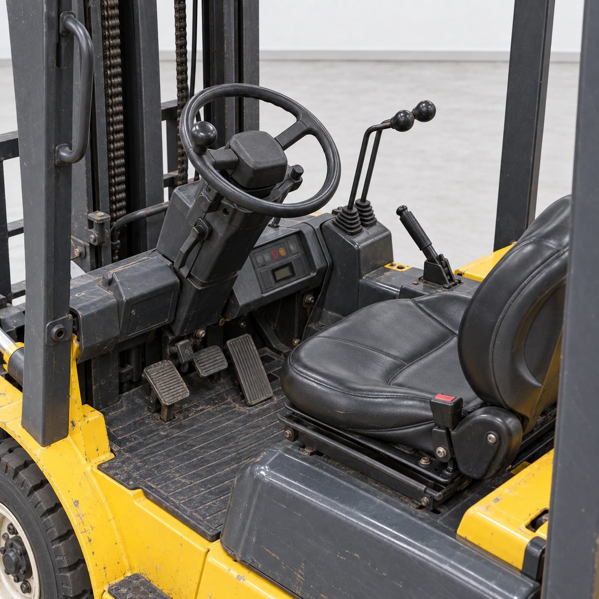 Empty operator seat, steering wheel, levers and pedals of a used yellow forklift