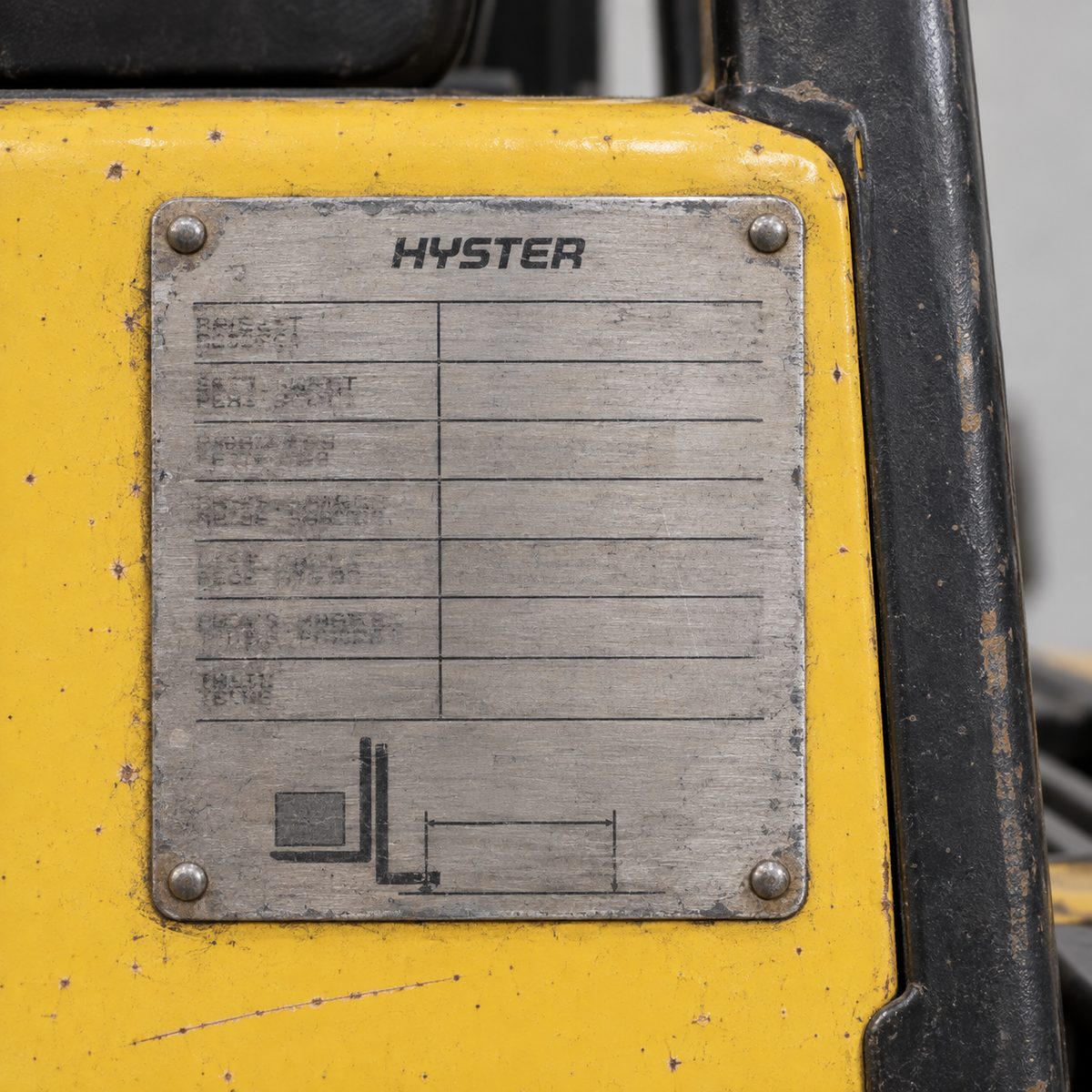Close-up of a forklift data plate with the Hyster brand name, other details blurred