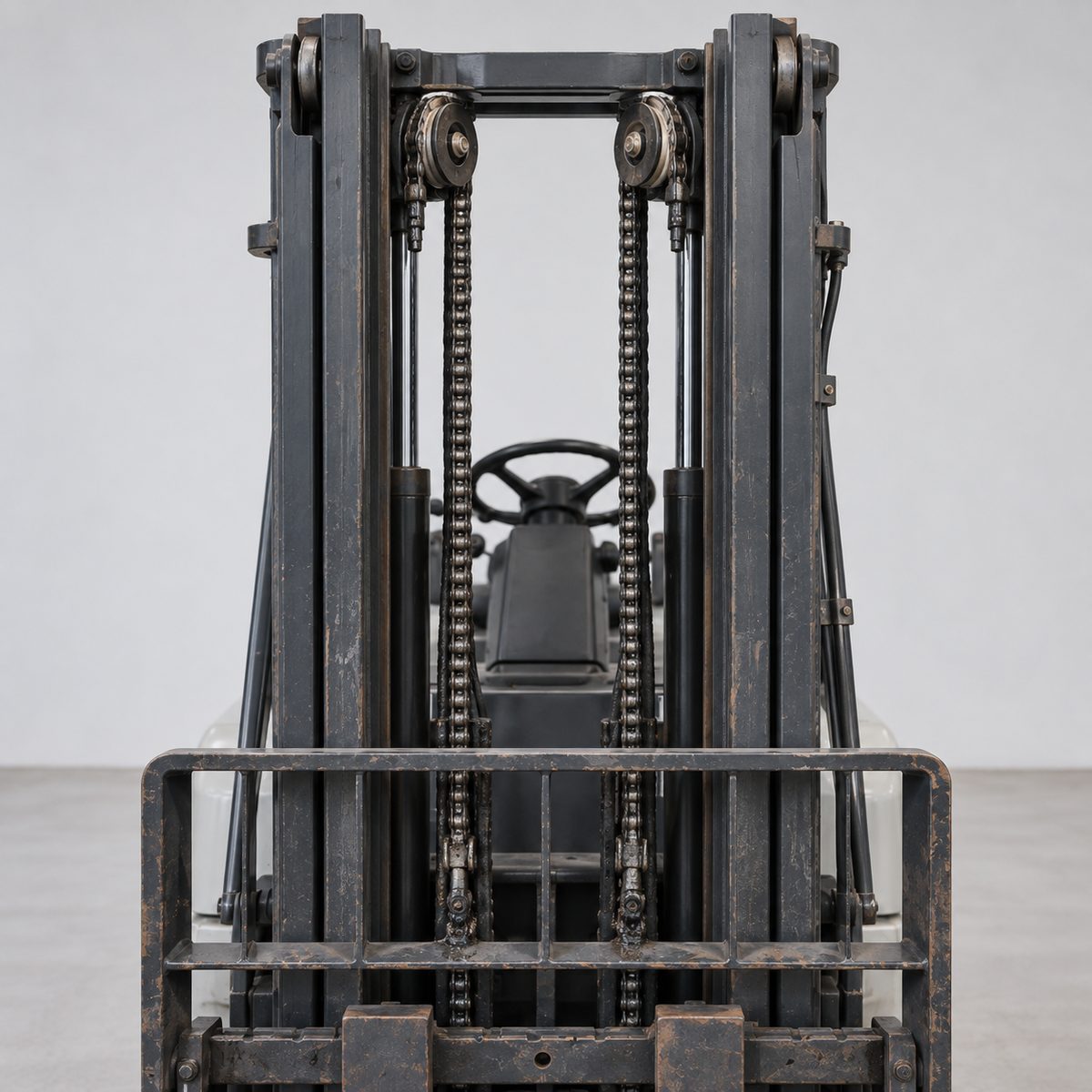 Close-up of a Komatsu forklift mast with two lift chains running over the top pulleys
