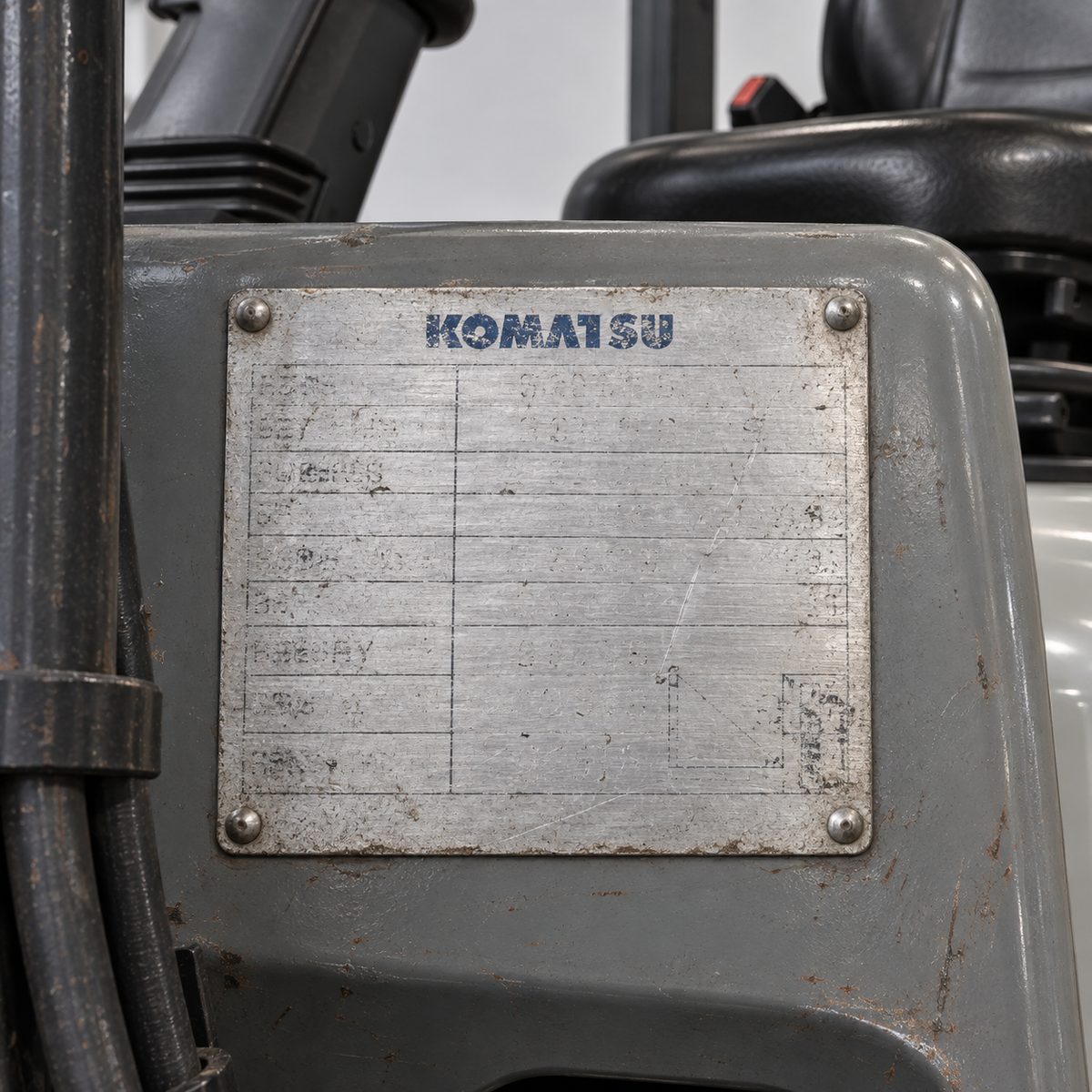Worn data plate riveted to a used Komatsu forklift with the details unreadable