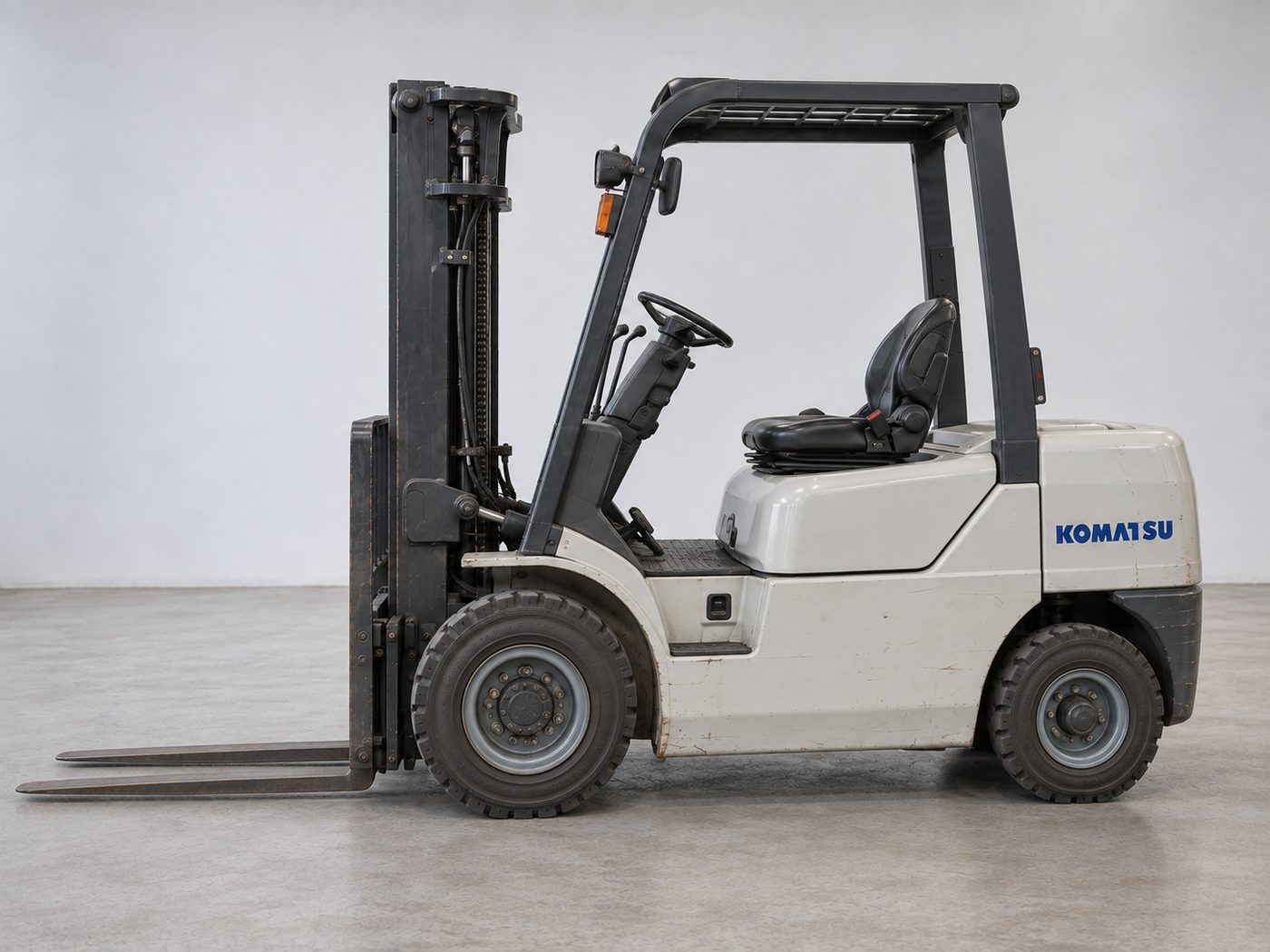 Side view of a used Komatsu diesel forklift showing the mast, seat and counterweight