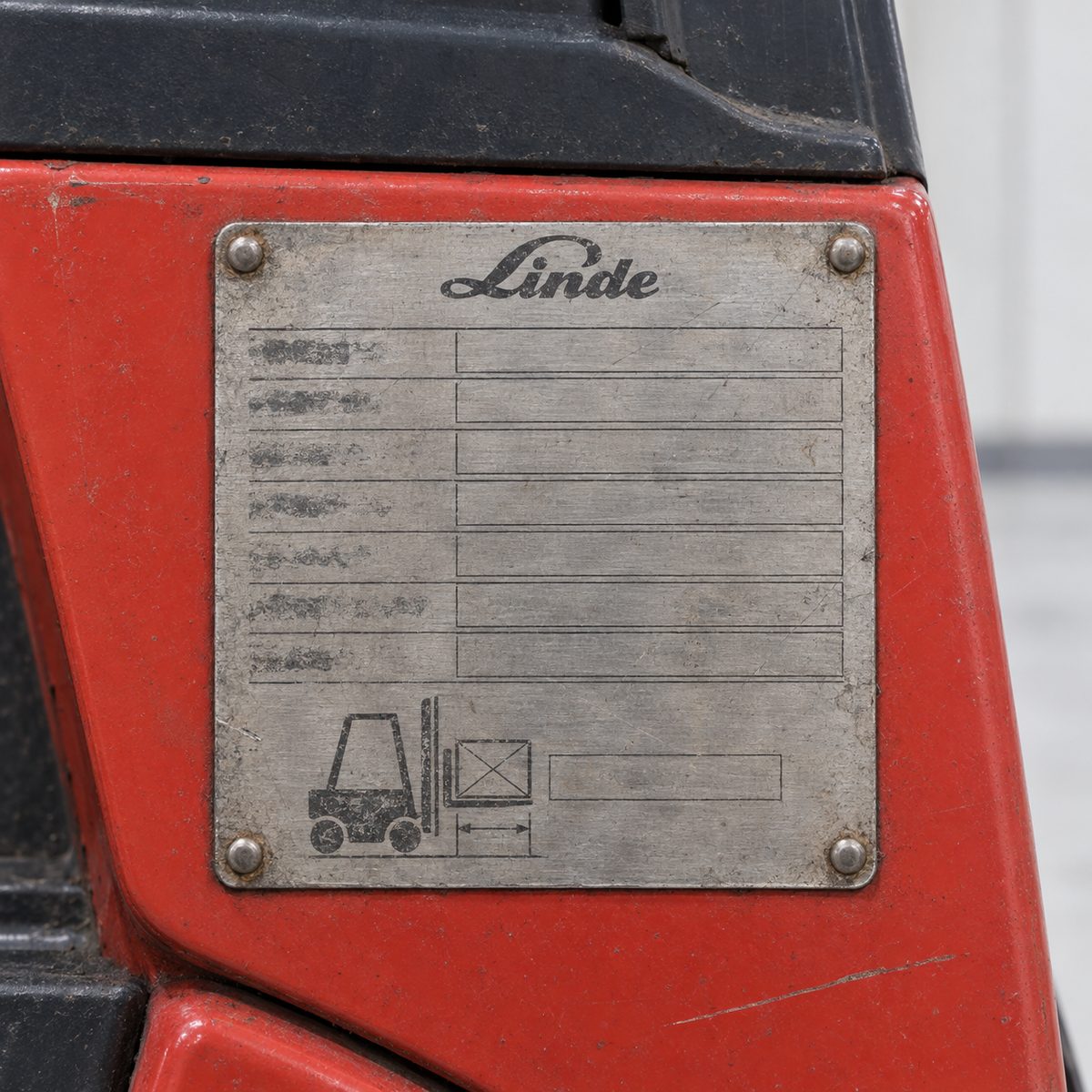 Worn aluminium Linde data plate with a load diagram on a red forklift panel