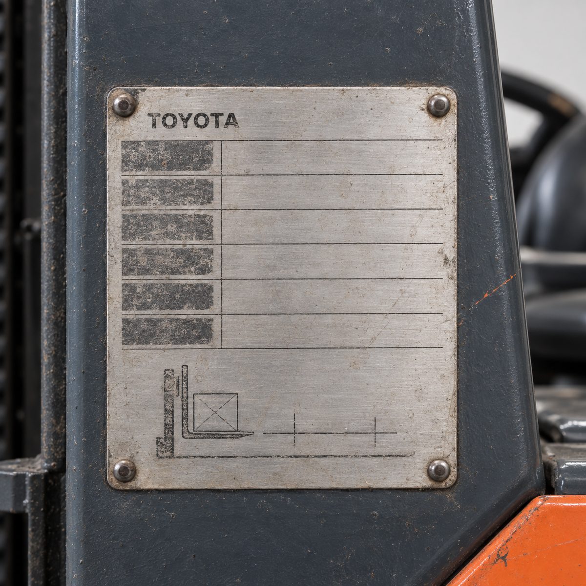 Worn aluminium Toyota data plate with four rivets on a dark grey forklift panel